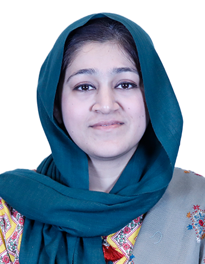 Portrait of a woman in a teal headscarf and a colorful embroidered shawl, smiling softly at the camera.